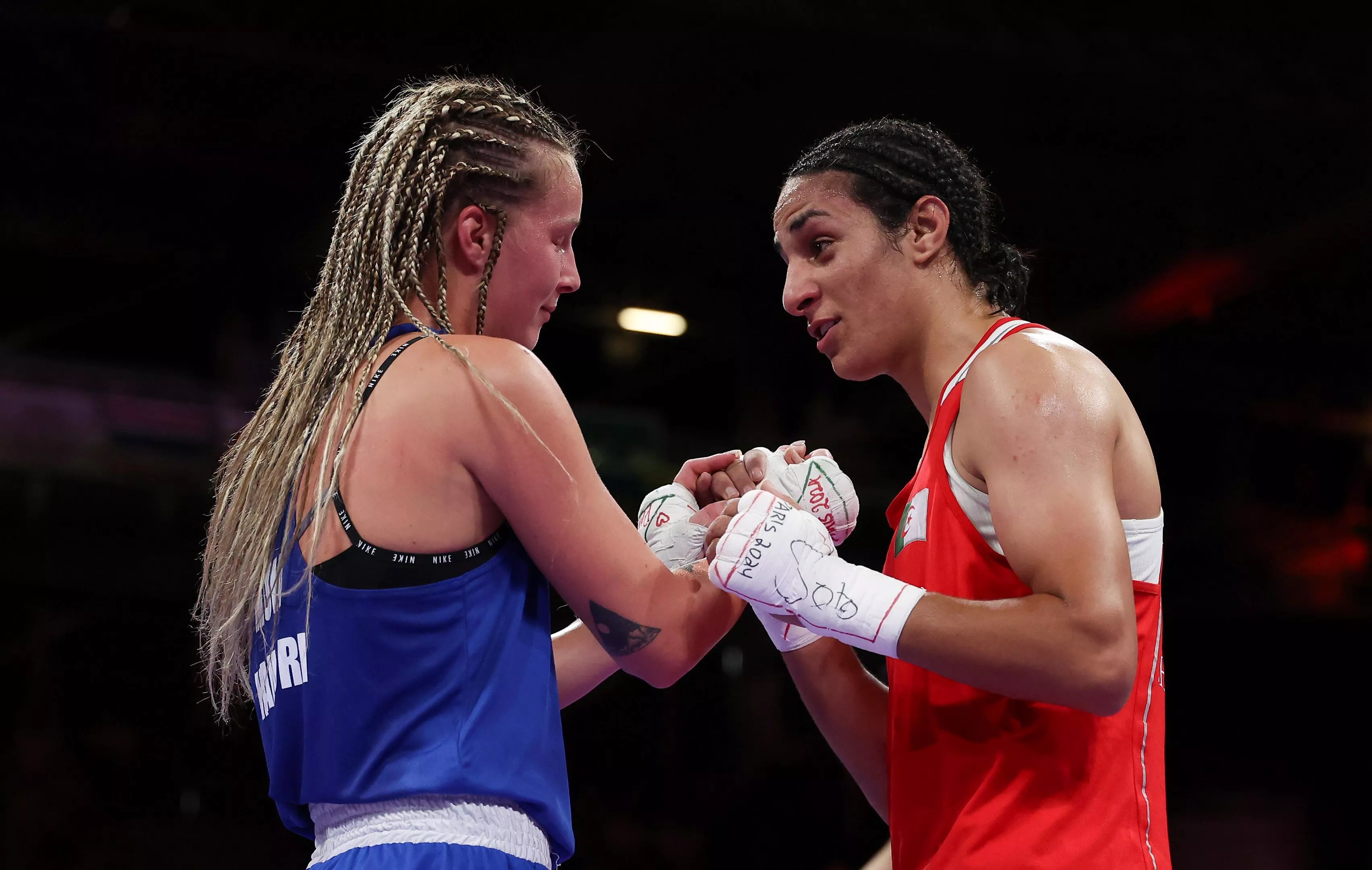 Two Olympic boxers clasp hands in the ring