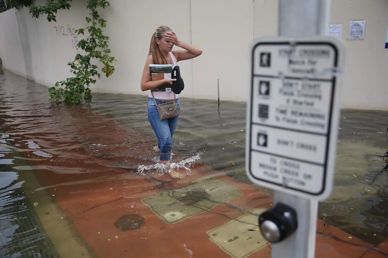 A woman walks through a street in Miami Beach that was flooded by the combination of the lunar orbit which caused seasonal high tides and what many believe is the rising sea levels due to climate change