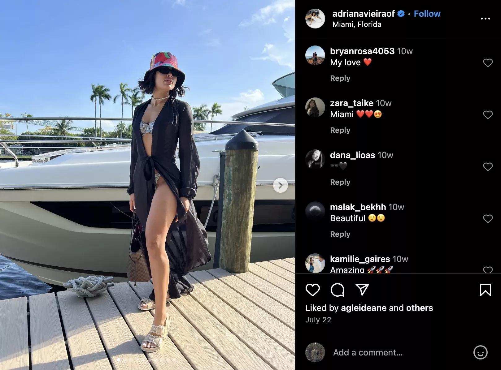 instagram screenshot showing a photo of a woman dressed in a bikini covered by a sheer robe, standing on a dock with a boat in the background