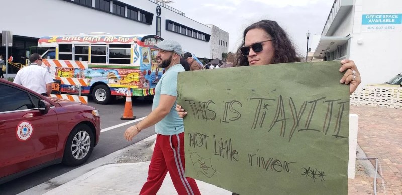 Man holding a signing reading "This is Ti Ayiti"