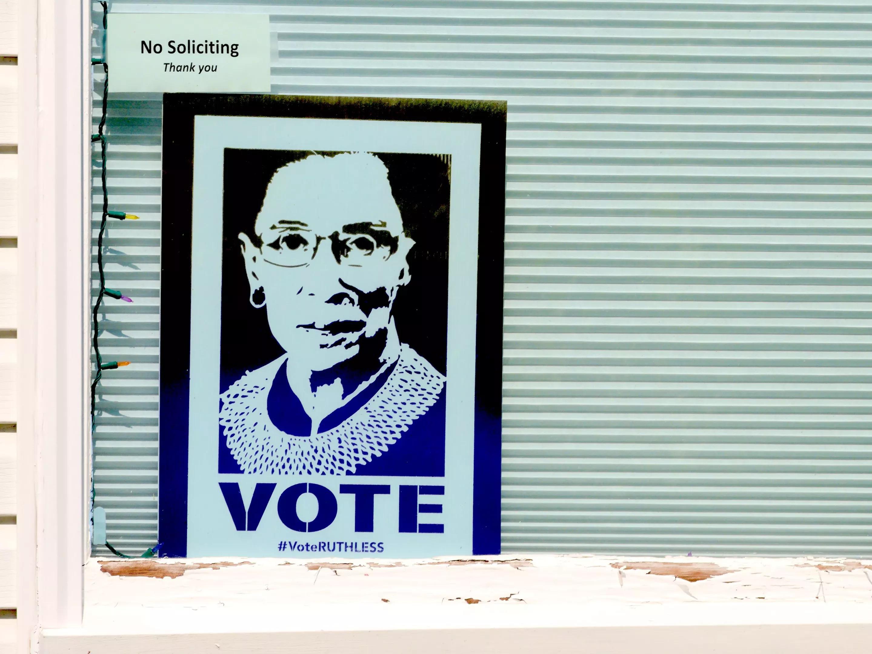small Justice Ruth Ginsburg "VOTE" poster displayed in a window underneath a smaller "no soliciting" sign