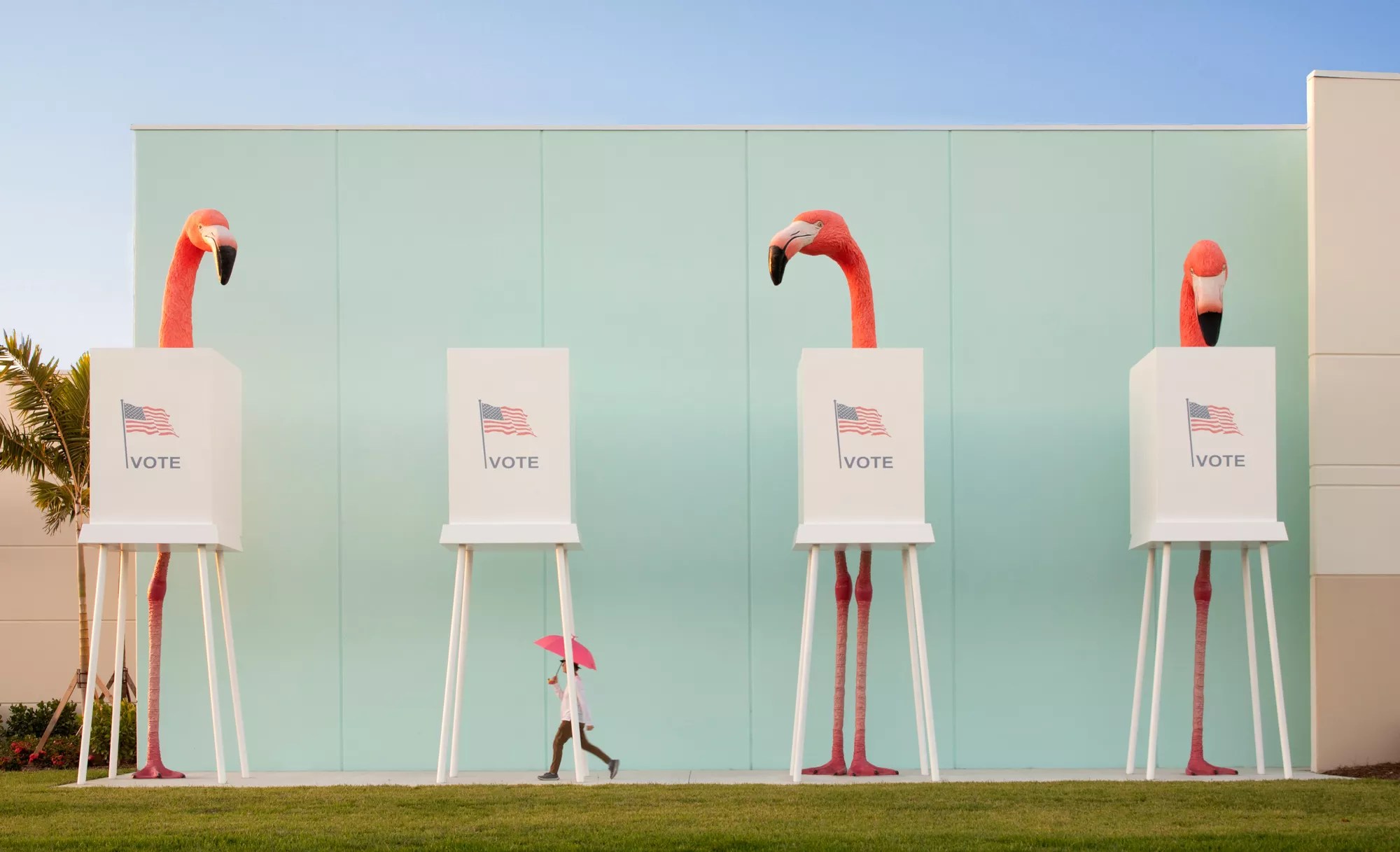 Three large flamingo sculptures standing at voting booths outside a building