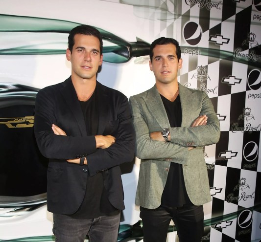 Twin brothers Alon and Oren Alexander stand with arms crossed while posing for photo at an event