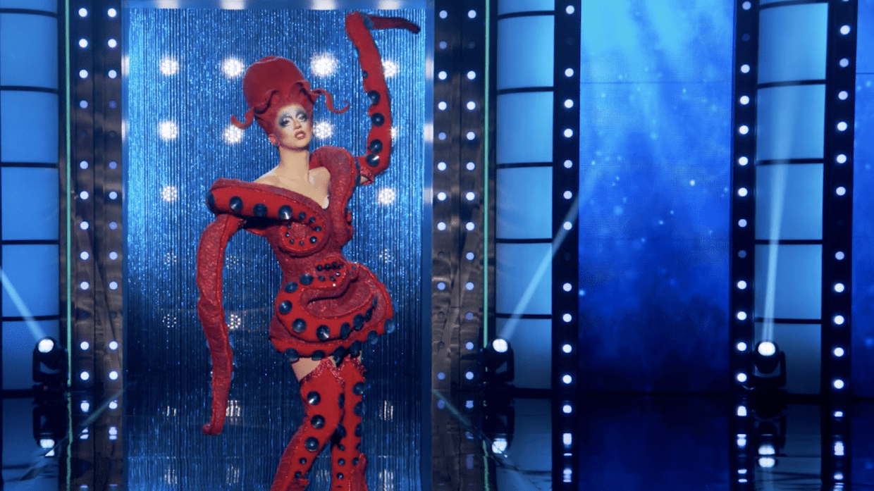 a drag queen walks the runway dressed as a red octopus
