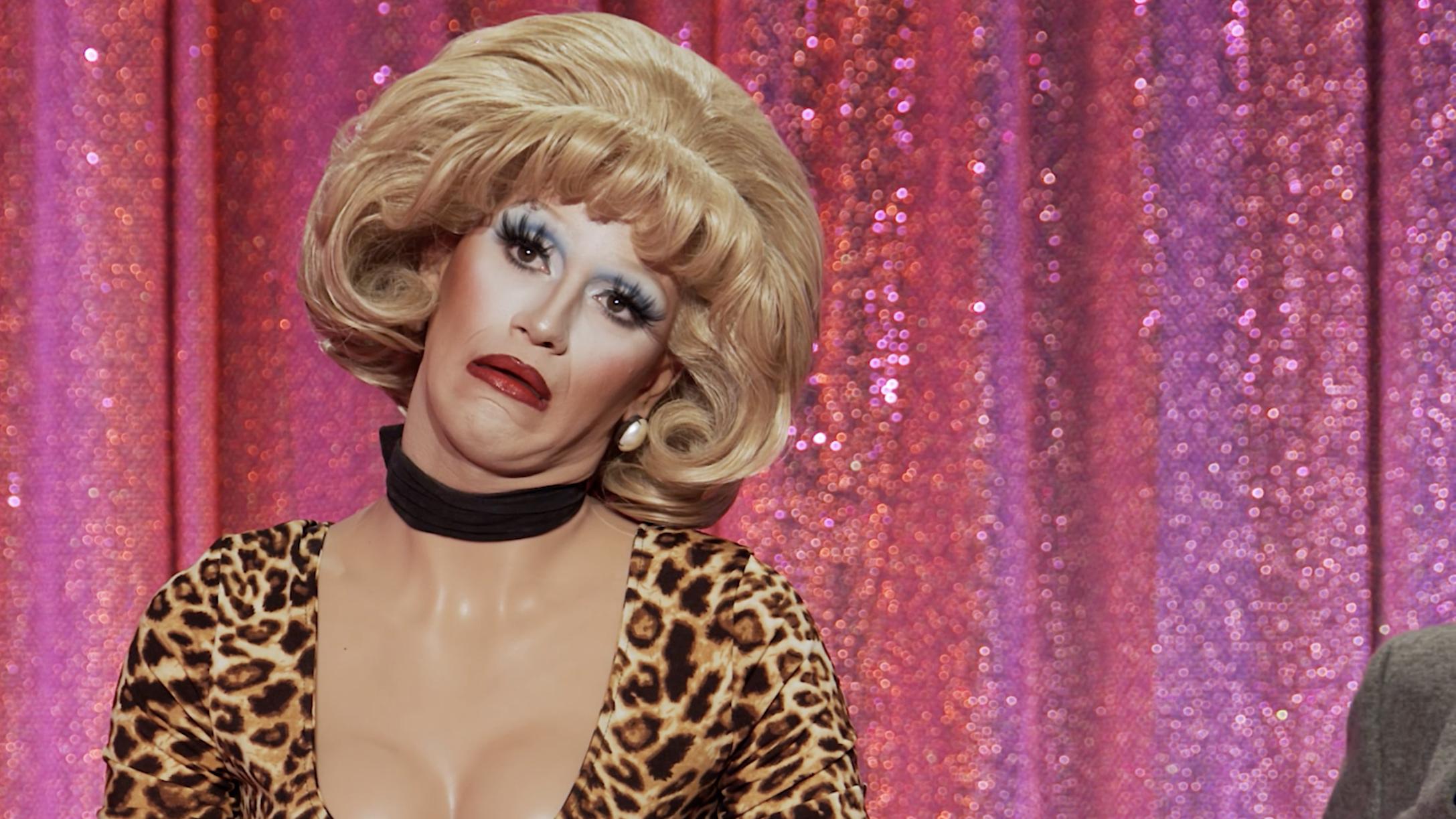 close-up of drag queen Suzie Toot wearing heavy makeup, a bog wig, and a leopard-print top