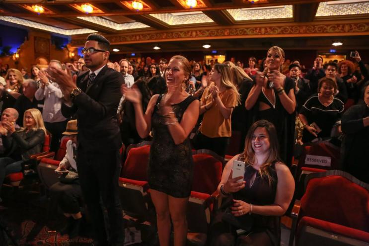 an audience claps inside a theater