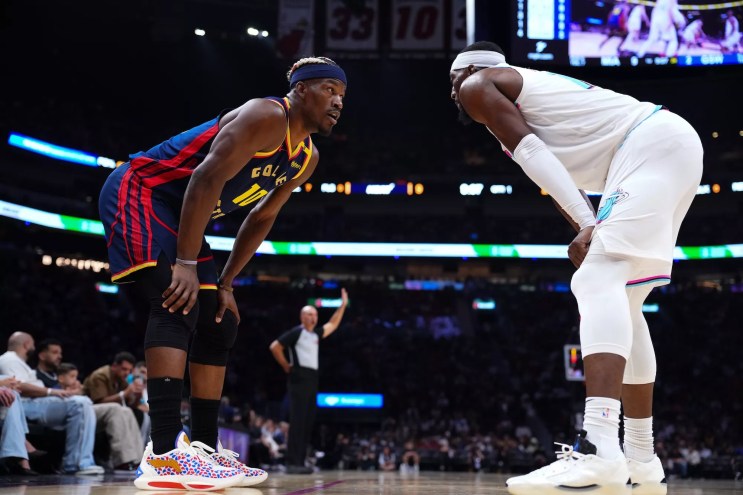 Jimmy Butler III #10 of the Golden State Warriors and Bam Adebayo #13 of the Miami Heat on the court during the first quarter at Kaseya Center on March 25, 2025, in Miami, Florida.