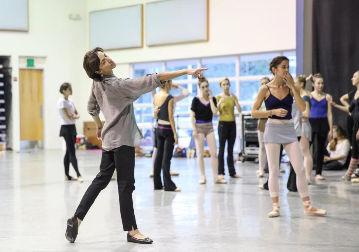 a ballet teacher poses in front of a class of students