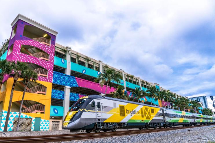 Brightline train in front of colorful parking garage in West Palm Beach