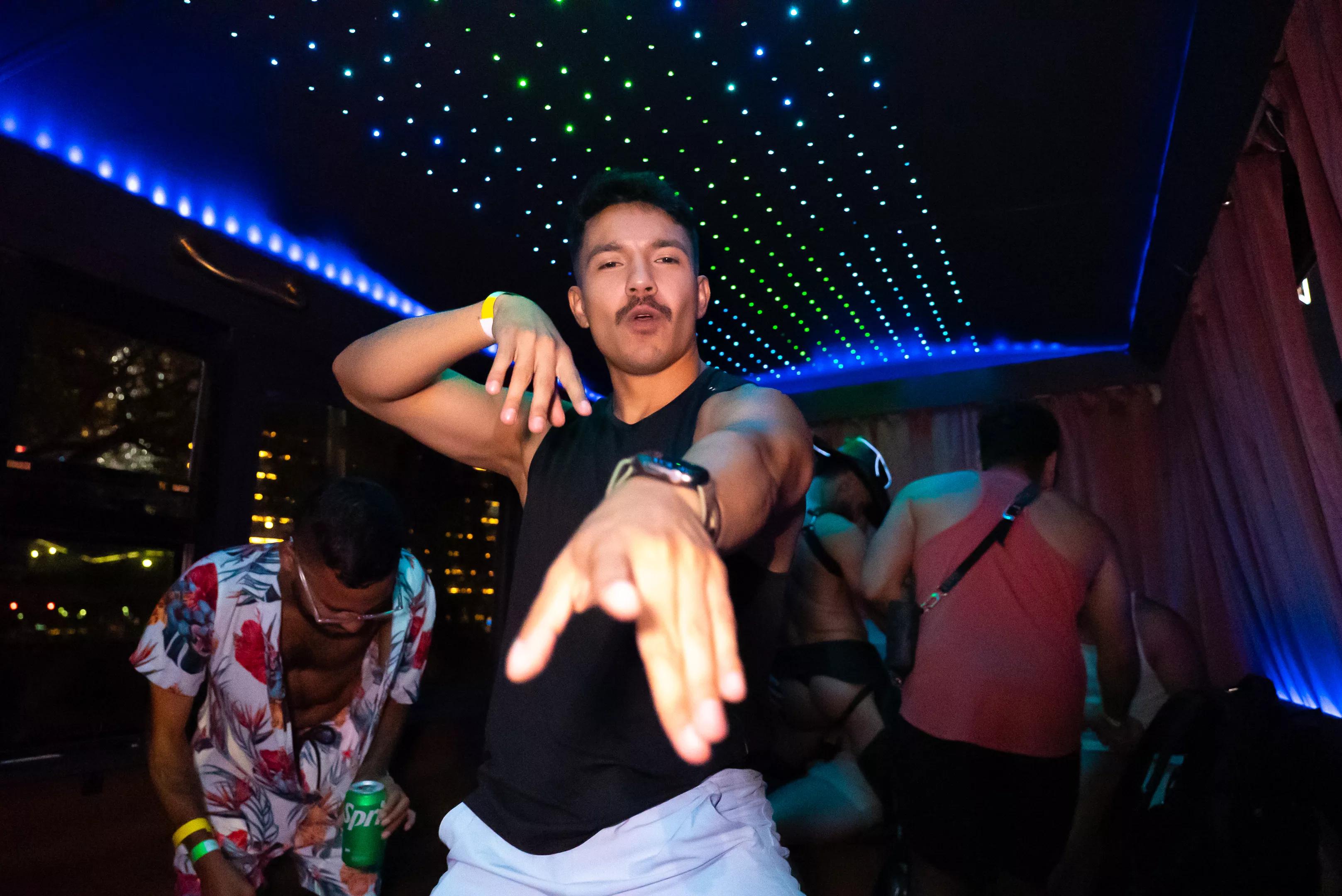 a man poses for the camera inside a neon-lit party bus