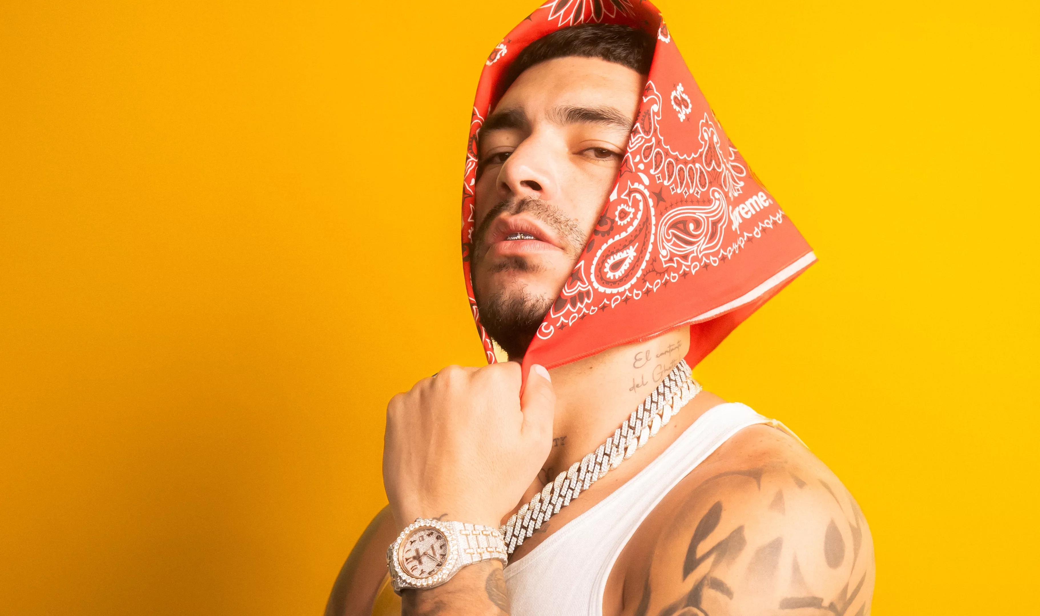 photo of rapper and singer Ryan Castro posing with a red handkerchief wrapped around his head in front of a yellow backdrop