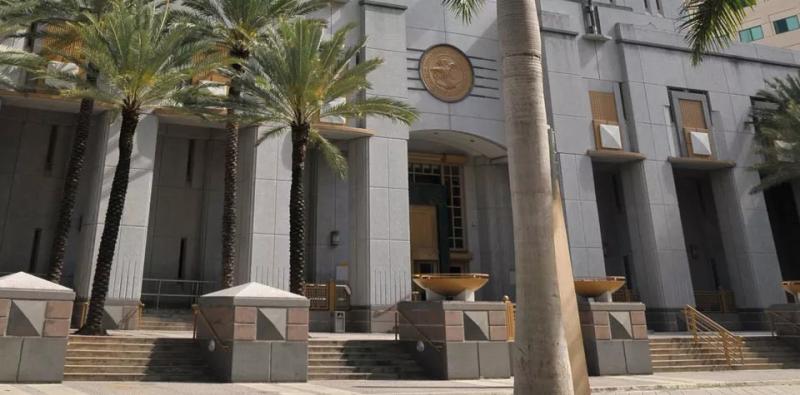 A white government building with three palm trees in front of it.