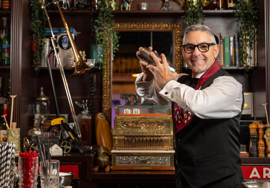 man behind bar shaking cocktail