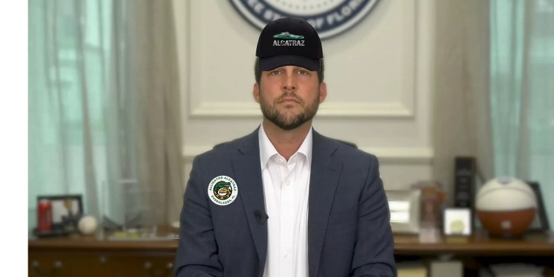 Florida Attorney General James Uthmeier wearing an alligator alcatraz hat and an alligator alcatraz button