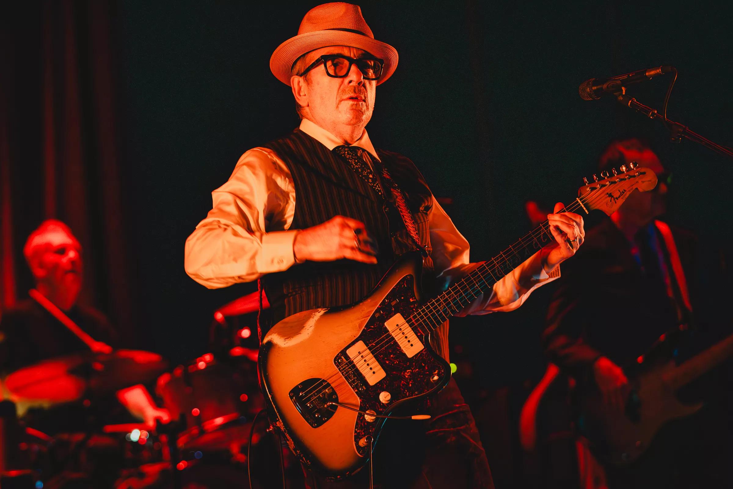 Elvis Costello playing his guitar at a live show
