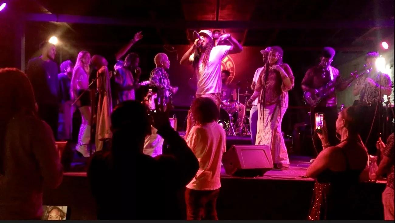Picture of a man with dreadlocks singing on stage