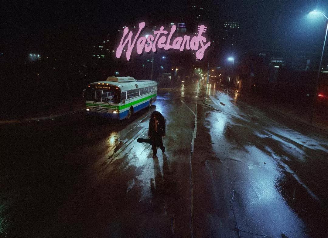 Image of a man walking at night carrying a guitar.
