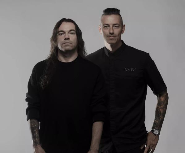 Two men posing for the camera wearing black.