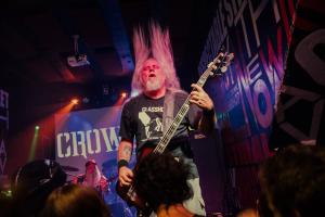 Bass player of a metal band performing in front of a crowd.