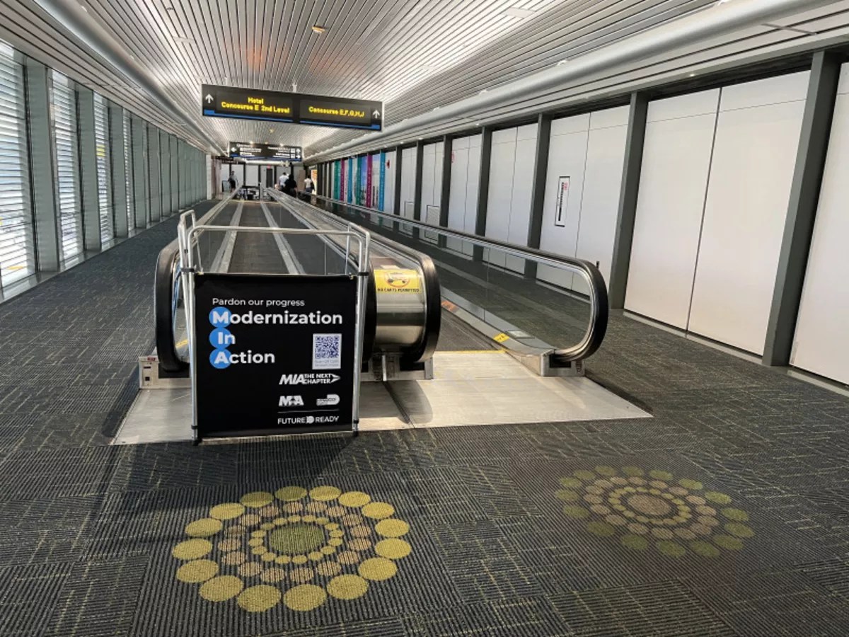 A sign that reads "Pardon our progress, Modernization In Action" blocks off access to an escalator.