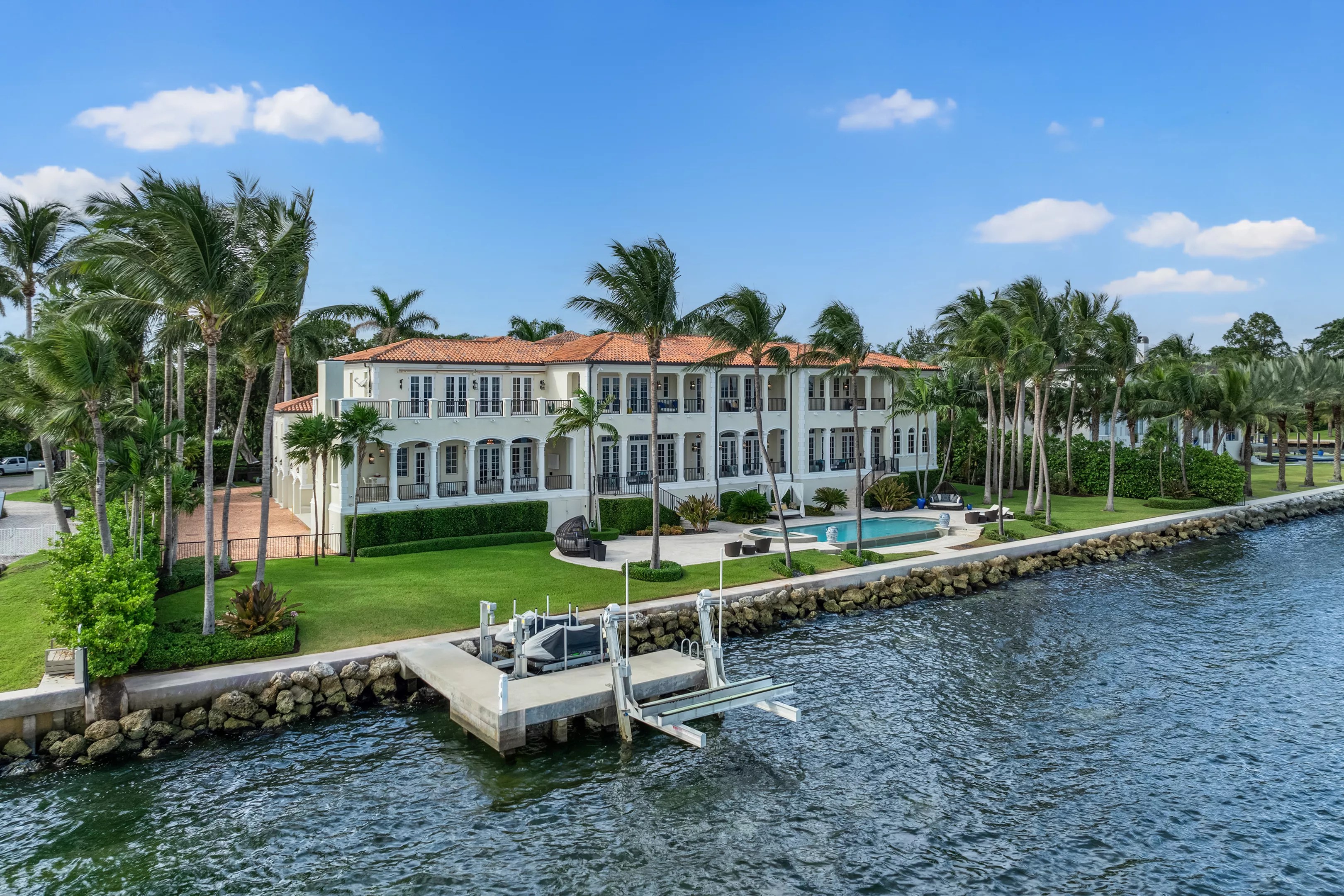 Backyard view of large cream waterfront mansion