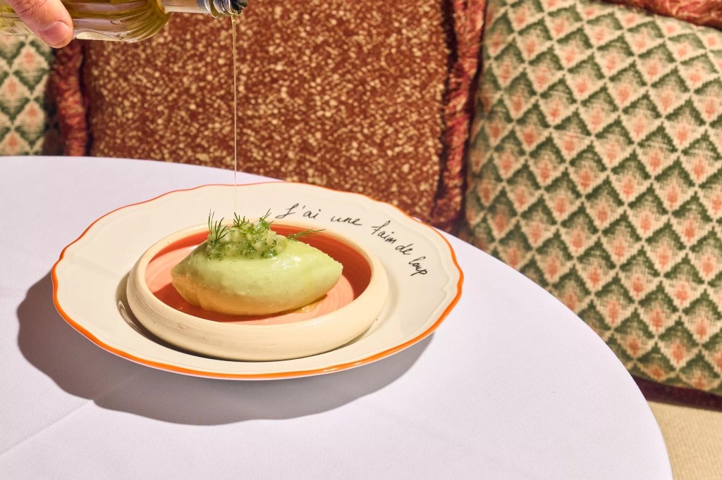 someone pouring sauce onto green dish