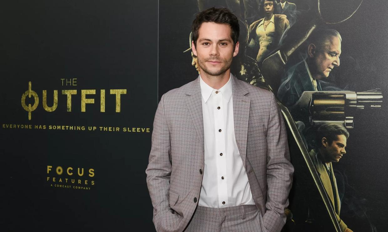 Actor Dylan O'Brien wears a suit on a red carpet at a film premiere.