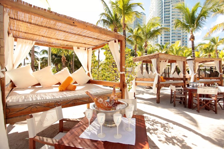 wooden cabanas and white furniture at Nikki Beach, a modern dayclub in Miami Beach